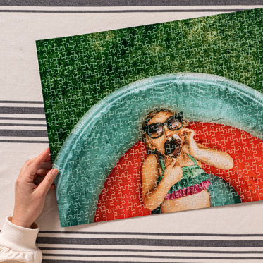 A hand holding a Photo Puzzle from Mpix featuring an image of a young girl in a swimming pool.