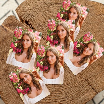 A set of wallet sized prints laying on a table that feature a photo of a high school senior girl.