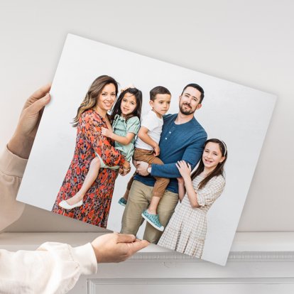 Hands holding a metal print from Mpix that features a photo of a family in front of a white background.