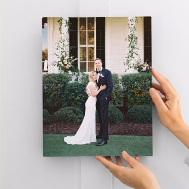 A Canvas Print Gallery Wrap from Mpix featuring a couple posing in front of a large house on their wedding day. 