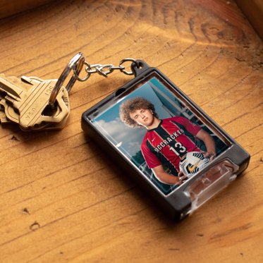 A personalized flashlight keychain with a custom photo of a high school athlete behind acrylic and showing the attached LED flashlight at the bottom. 