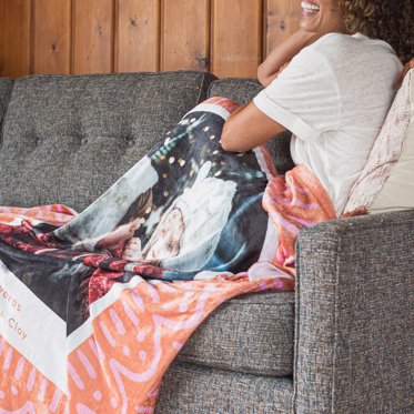 Woman under a Personalized Fleece Blanket from Mpix decorated with family photos. 