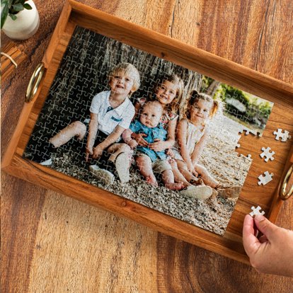 An assembled photo puzzle featuring four young kids sitting outside under a tree. 