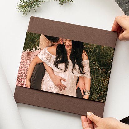 Mpix Hardcover Photo Book with brown linen cover and skinny dust jacket featuring a couple embracing for their engagement photos. 