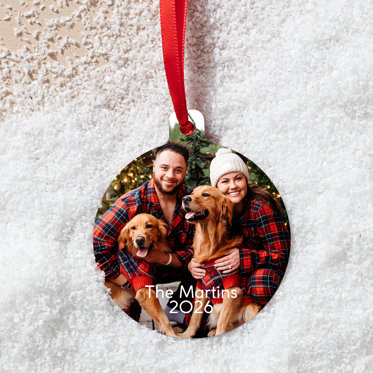 A circular metal ornament featuring a photo of family in Christmas pajamas.
