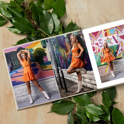 An open photo book with the interior pages featuring images of a high school student from her senior photo shoot.