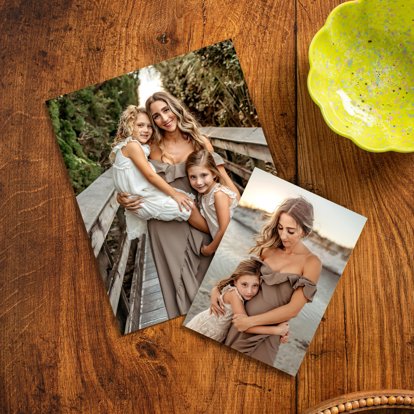 Two photo prints lying on a table featuring a mom with her two young daughters on a beach. 