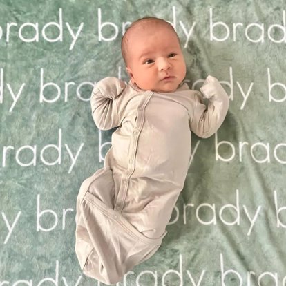 A baby laying on a name blanket.