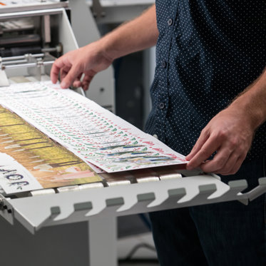 Freshly printed greeting cards on a professional printing press, featuring colorful and festive designs.