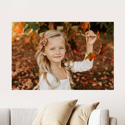 A large Metal Print displayed on a wall above a couch and featuring a fall image of a young girl.