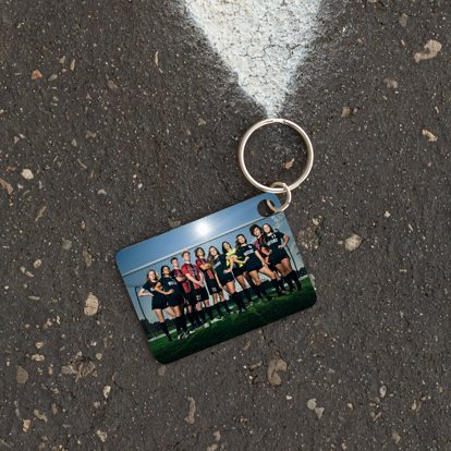 metal keychain with a photo of a ladies soccer team resting on the asphault