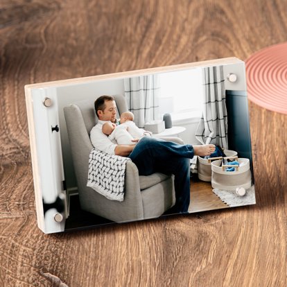 A horizontal birch photo block displayed on a table featuring a photo of a dad in a recliner holding his twin babies.
