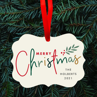 Holiday Ornament with a merry christmas message hanging from a christmas tree with a red ribbon