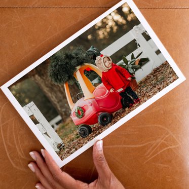Softcover photo book from mpix on a leather seat with a large image cover of a toddler standing next to his big wheel christmas gift. 