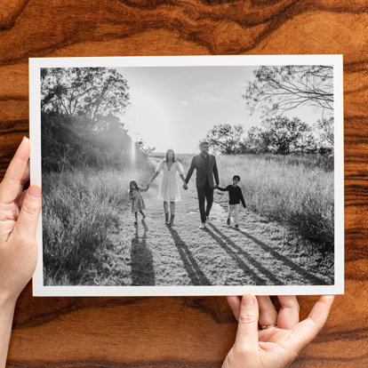 A person holding a Black & White Print of a family walking in a field.